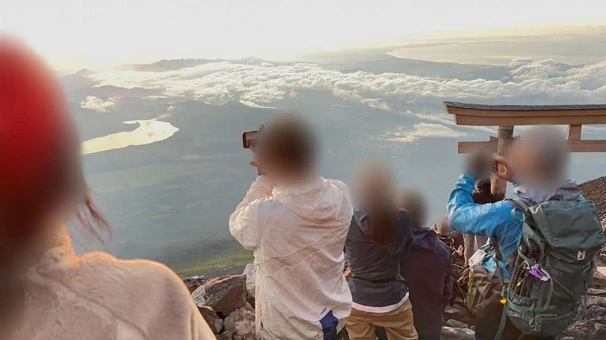 山頂から景色を見る登山者たち。全員の顔と頭部は匿名化済み